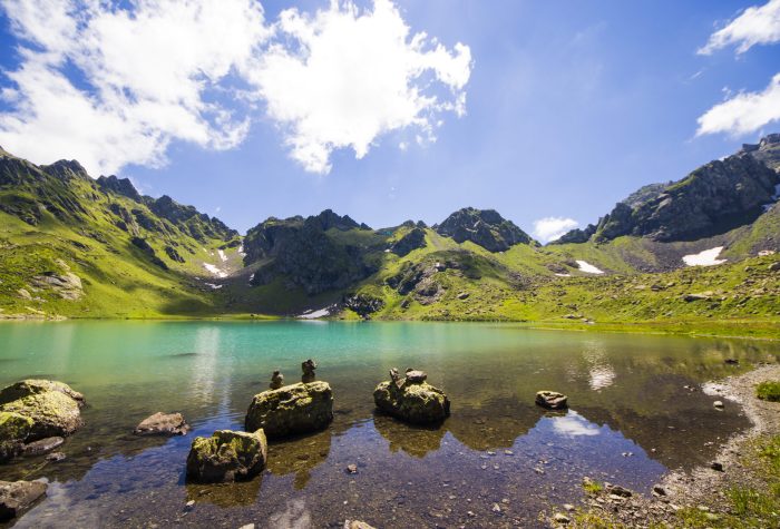 Alpine mountain lake landscape and view, blue beautiful and amazing lake panorama, wide angle lens landscape and mountain reflections in Okhrotskhali in Svaneti, Georgia.